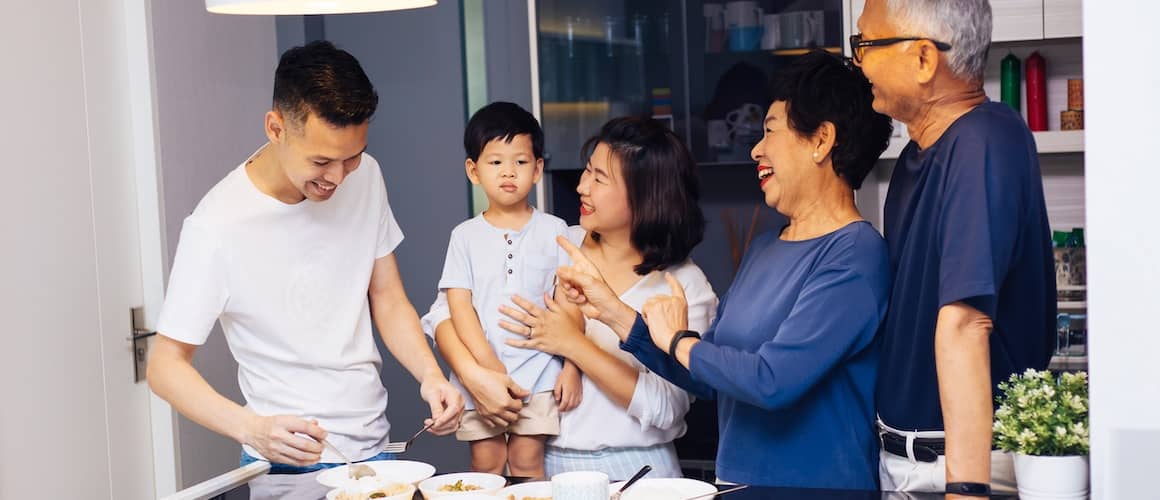 Family gathered around food in kitchen.