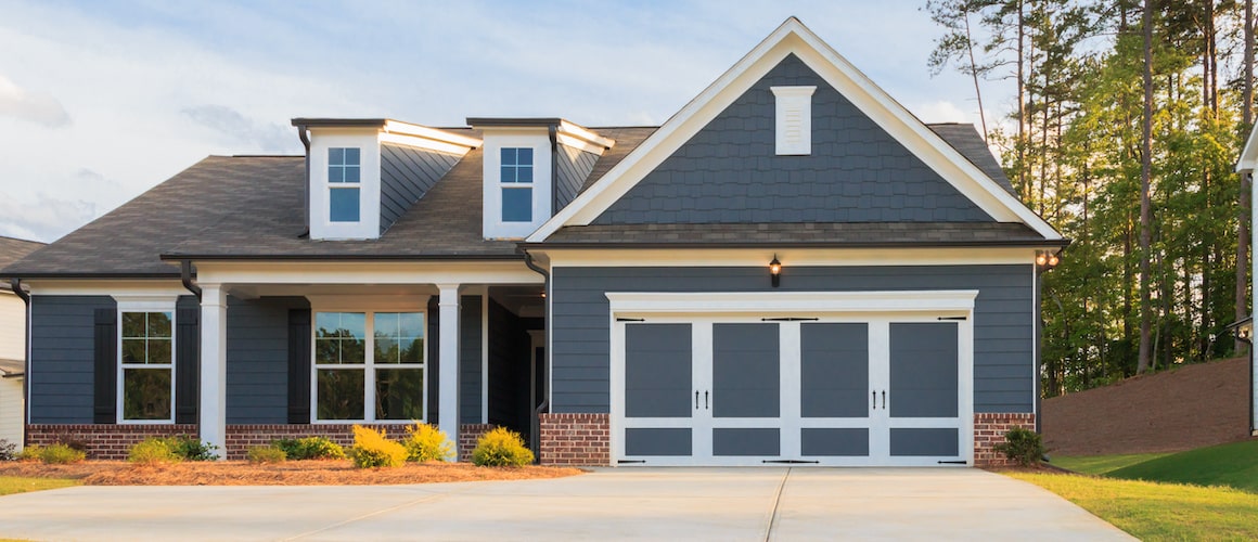 Exterior view of a gray ranch-style home with a driveway and surrounding greenery.