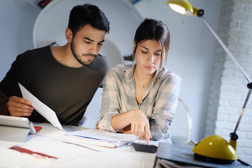 Young couple reviewing invoices and doing family business plan. 