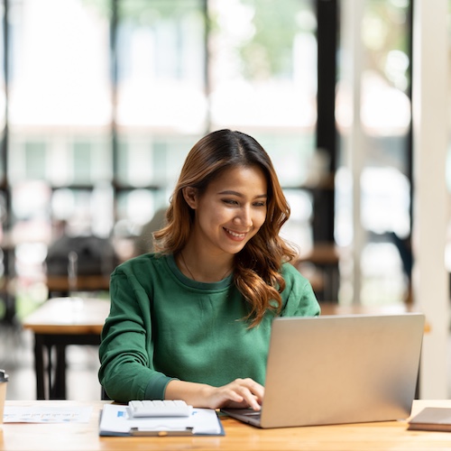 Woman wearing a green shirt using a laptop.