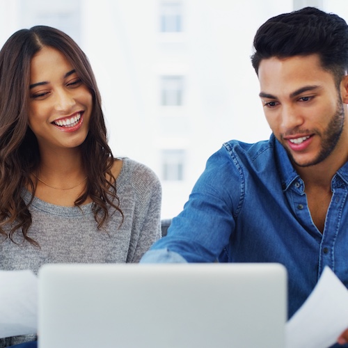 Couple smiling while reviewing their mortgage together on couch.
