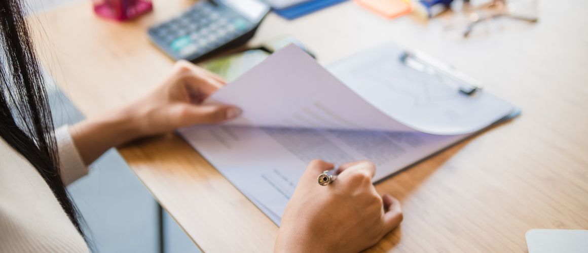 A woman signing paperwork, likely related to legal or financial documentation.