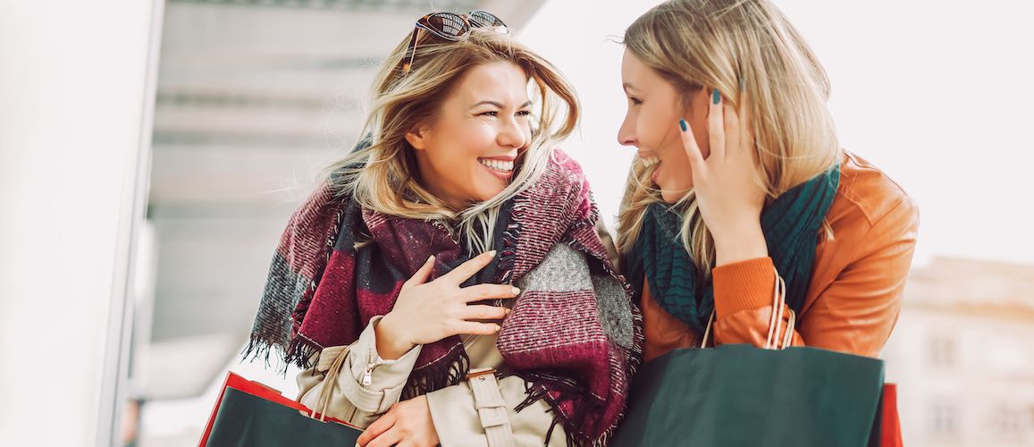 Two blonde women smiling and talking.