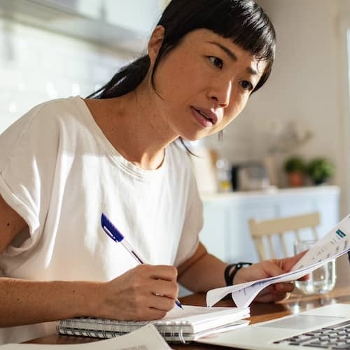 Woman calculating her finances and budget at her kitchen table.