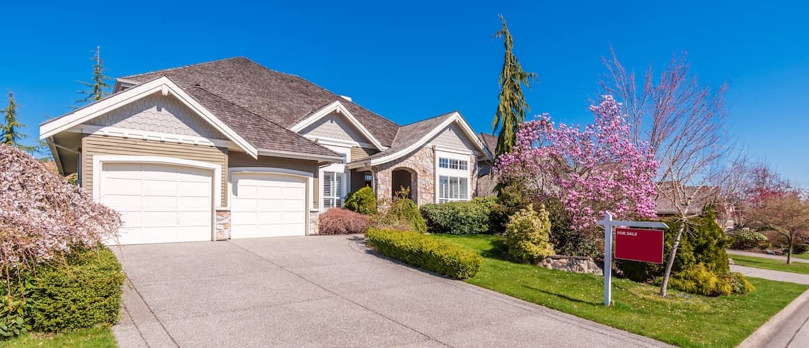 Ranch-style home with tan siding, stone accents and a beautifully manicured lawn.