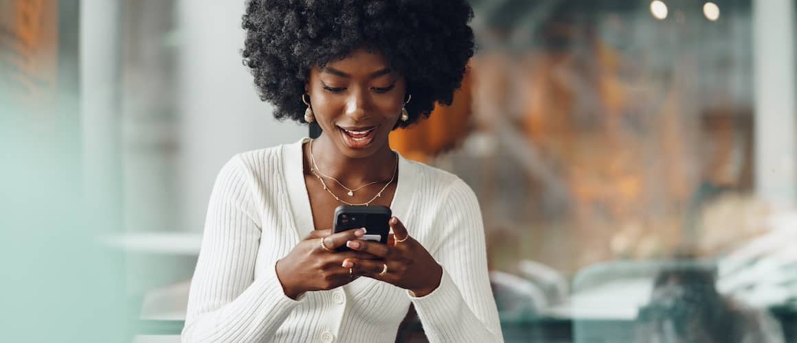 Young woman looking down at her cell phone while using it.