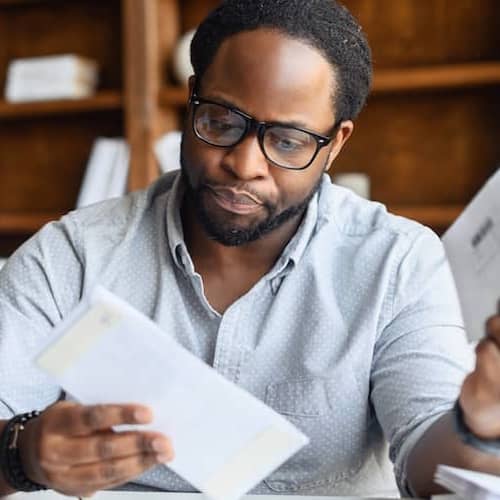 A man reviewing bills at his desk.