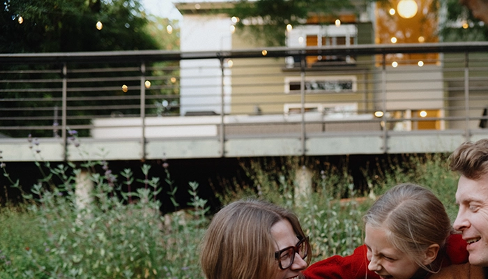 Young girl in red sweater hugging her smiling parents.
