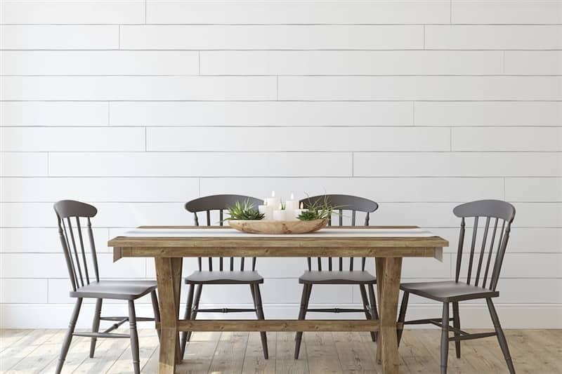 RHB Assets From IGX: A modern dining room with a large wooden table, white walls with a shiplap accent wall, and black chairs.