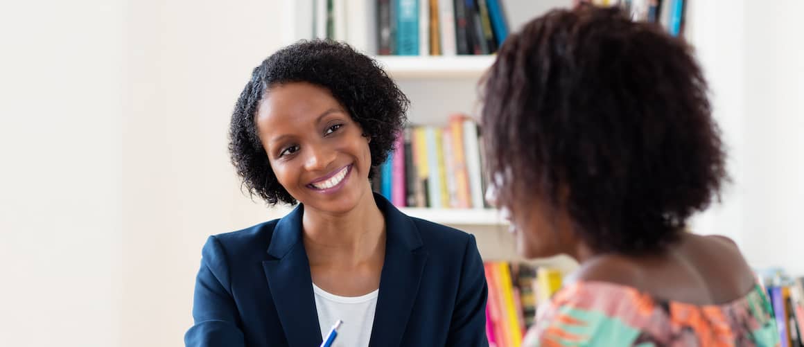 An African American woman signing a contract, potentially related to real estate or homeownership.