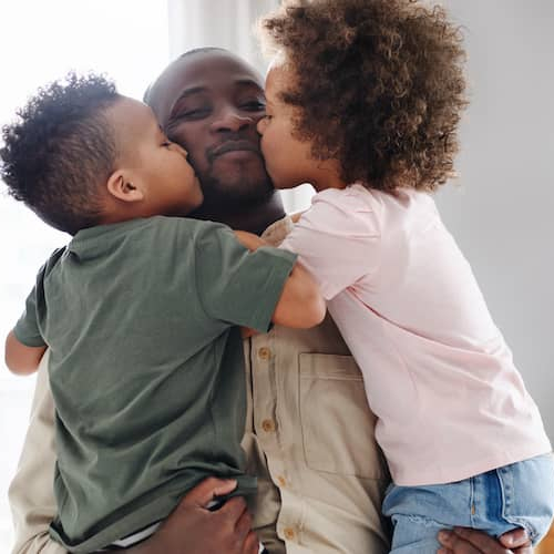 A man and two children sharing a heartfelt embrace in a cozy living room.