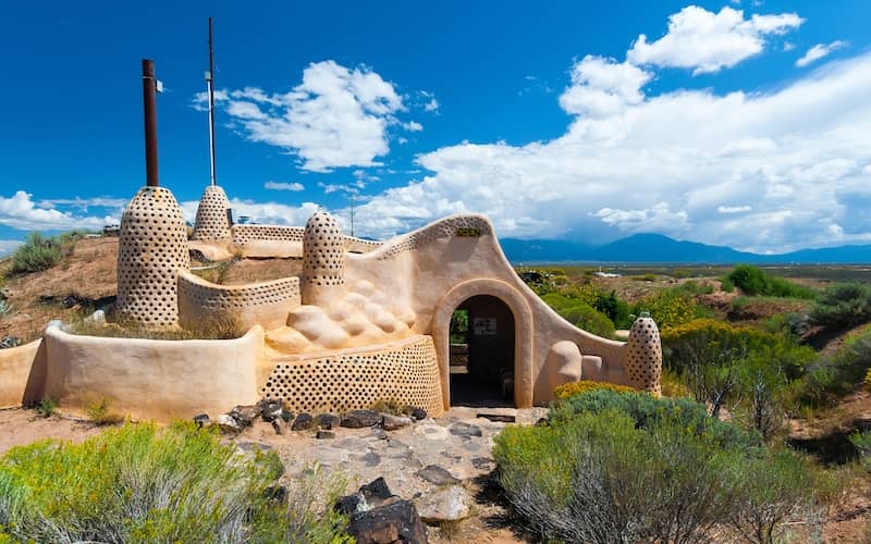 Earthship business with open sign hanging over the front door on a partly sunny day. 