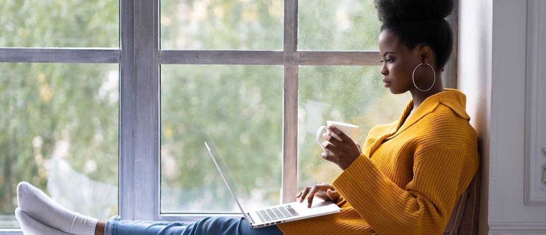 Woman in orange sweater on computer.