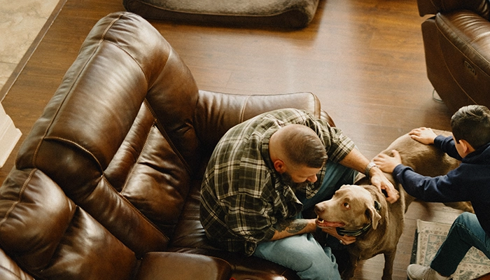 Father and son petting dog in living room.