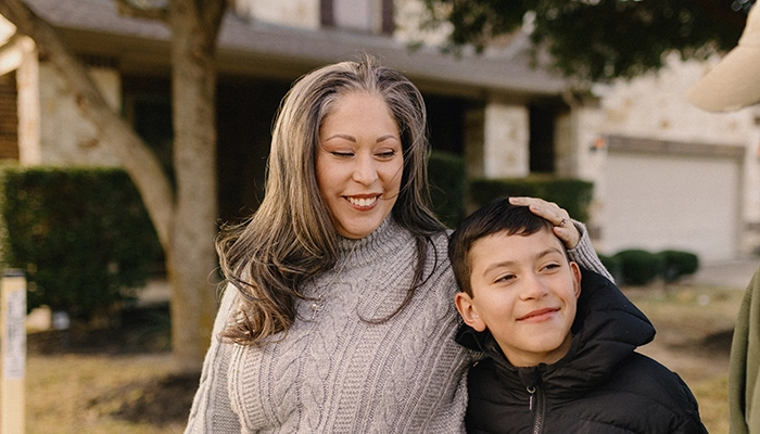 Woman holding kid's head smiling.