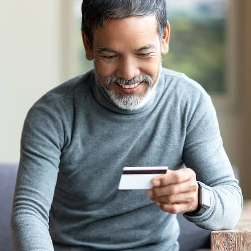 Image of man smiling and looking down at credit card.