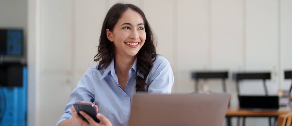 Woman smiling as she opens bank account on computer.