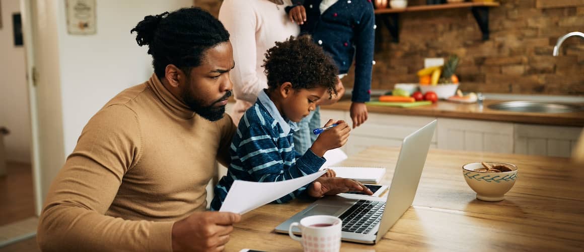 Father holding young son while he does paperwork at home.