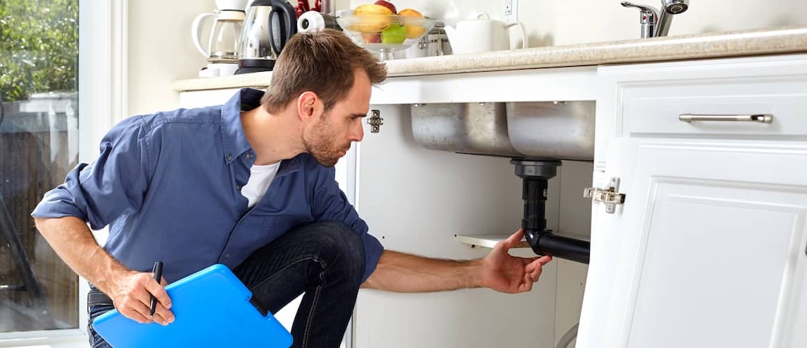 Plumber Inspecting Sink In House