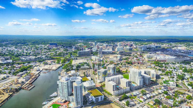 RHB Assets From IGX: Aerial view of Stamford, Connecticut, with a mix of residential and commercial buildings, green spaces, and waterways.