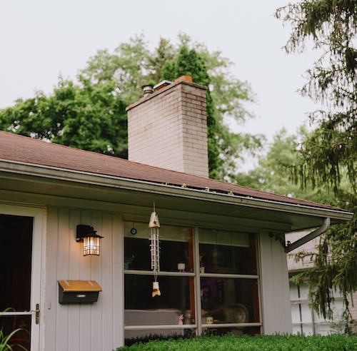 Small light grey home with porch light.