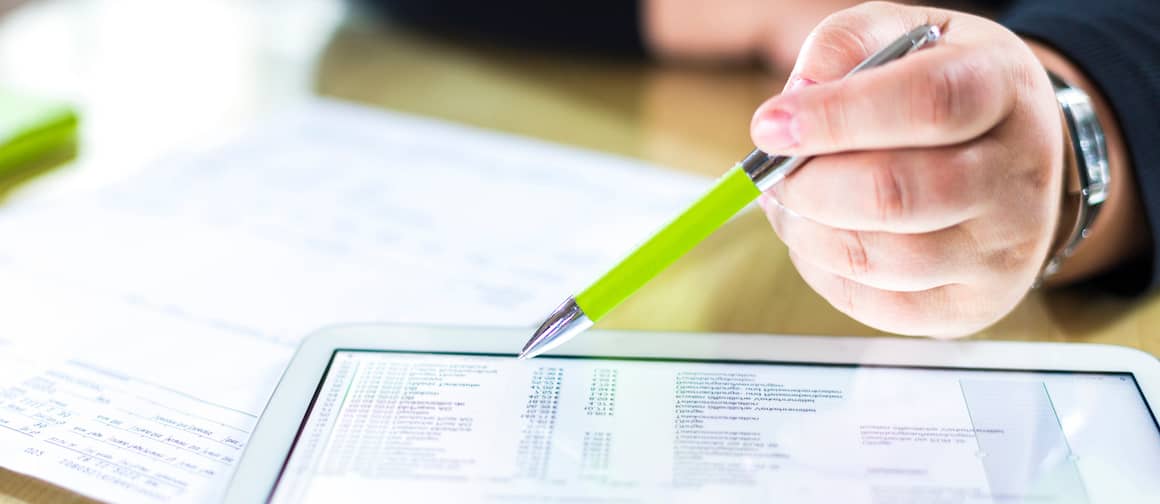 Closeup of hand as someone budgets on a tablet.