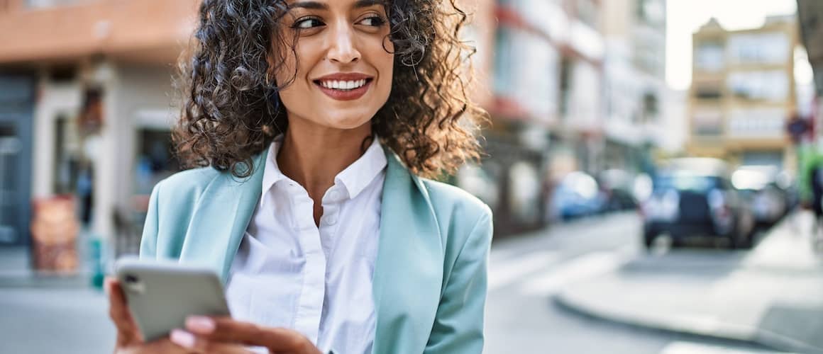 Woman walking through city, smiling.