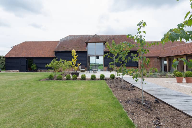 Converted barn with outbuildings attached featuring a covered walkway with vast land surrounding the property.