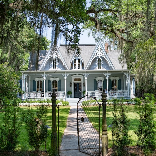 Large home in Louisiana with moss-covered oaks in the foreground.