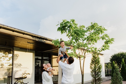 Young family playing in yard of their modern ranch style home.