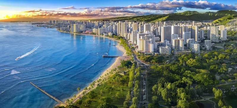 View of oceanside trees and buildings stretching into a vast ocean view at horizon.