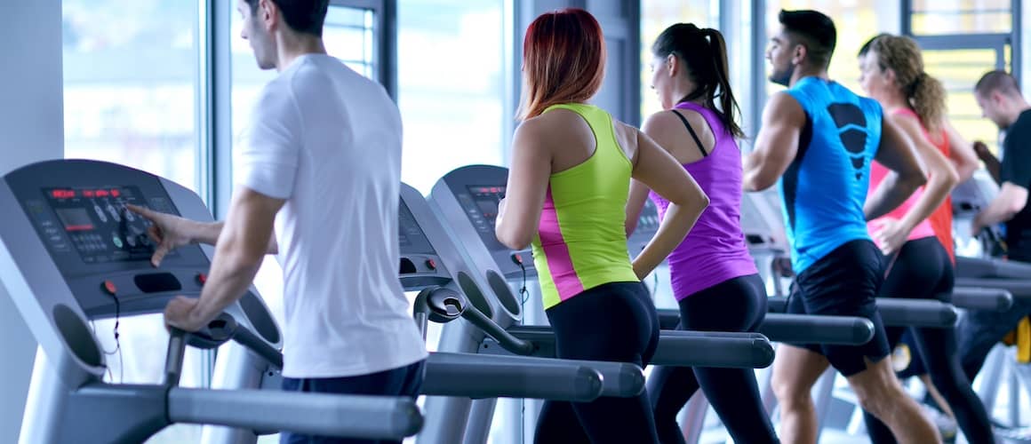 Line of people running on treadmills in a gym.