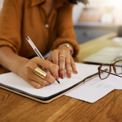 Woman calculating finances on paper with a laptop nearby.