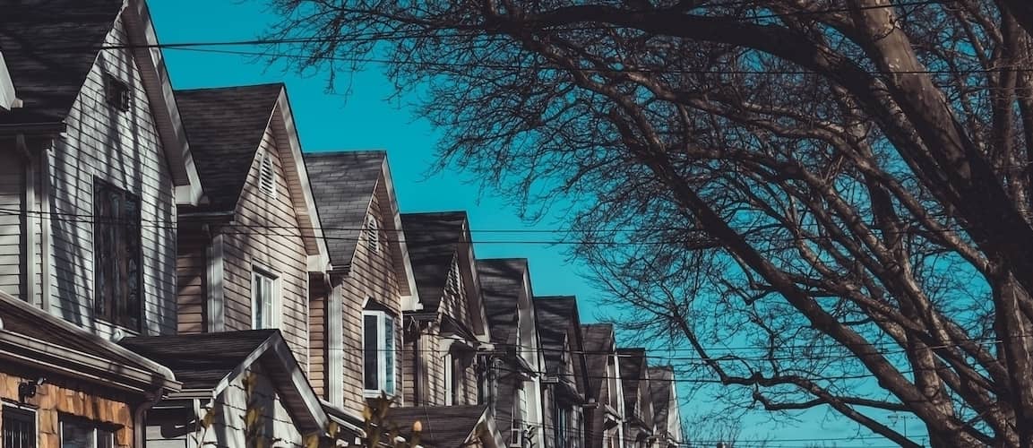 A suburban neighborhood with houses, trees, and power lines lining the street.