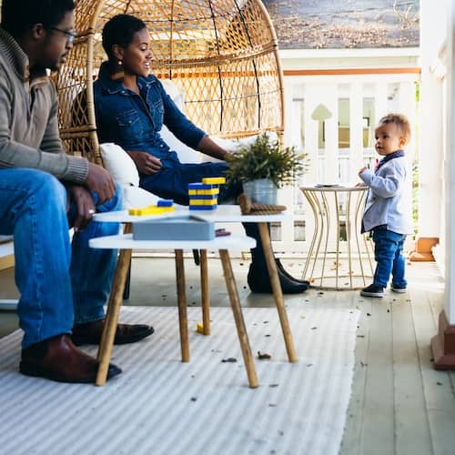 A mom and dad hanging out on their front porch, playing with toddler son.