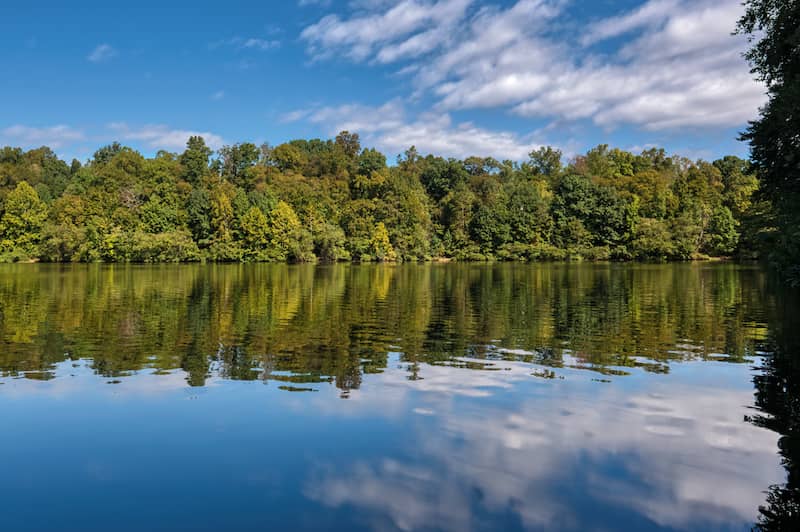 RHB Assets From IGX: A serene lake in Montclair, Virginia during a clear day with blue skies and trees surrounding the lake