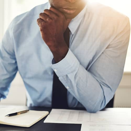A man carefully reviewing documents related to real estate or financial matters.