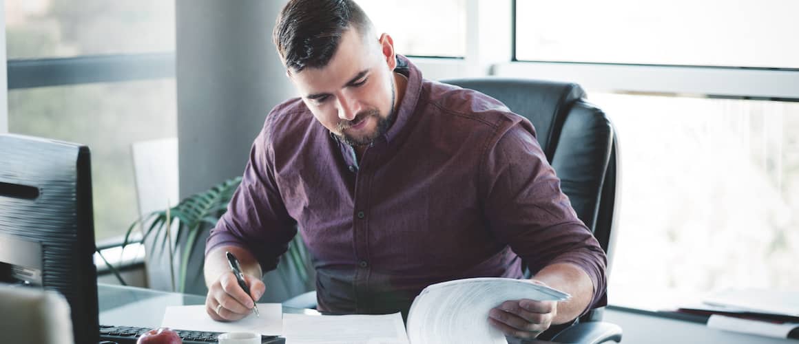 Businessman looking through a binder on his desk in his office.