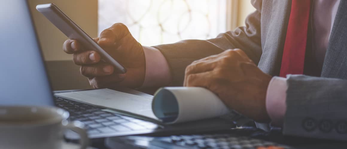 Businessman's hands using a calculator at a desk.