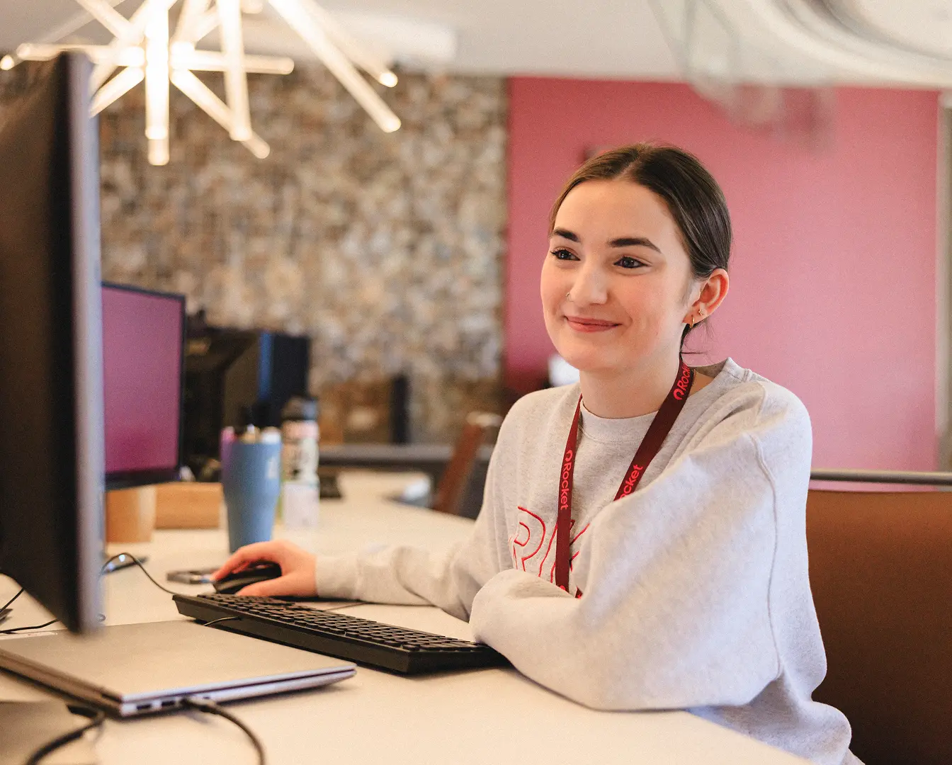A Rocket team member smiling while she is working on the computer at her desk. 