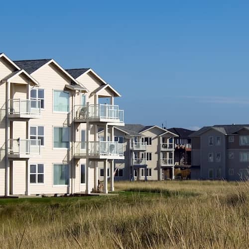 Luxury oceanfront condos surrounded by beach grass on a clear, sunny day. 