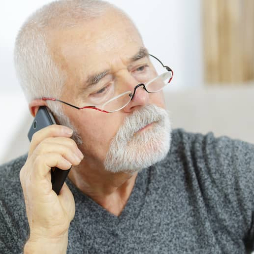 An older man on the phone looking at bills, potentially managing household expenses or discussing financial aspects of homeownership.
