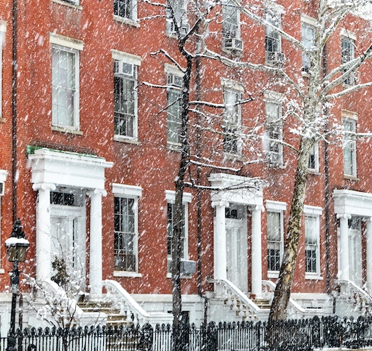 Townhouses in New York City while it snows in winter.