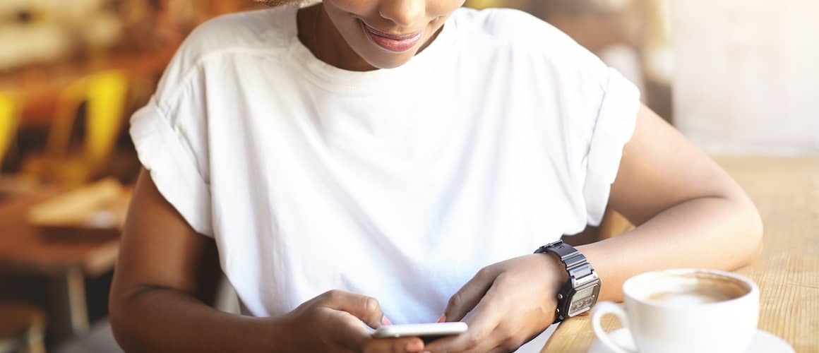 Woman reviewing her credit score on her phone in a cafe. 