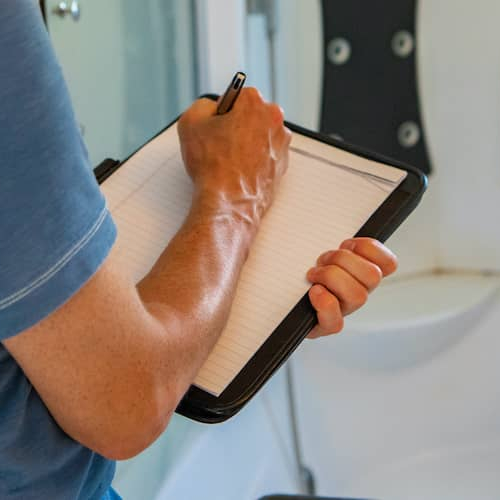 Contractor writing inspection checklist while renovating a bathroom.