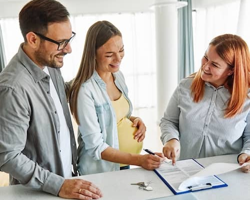 Young couple signing paperwork to buy a new home.