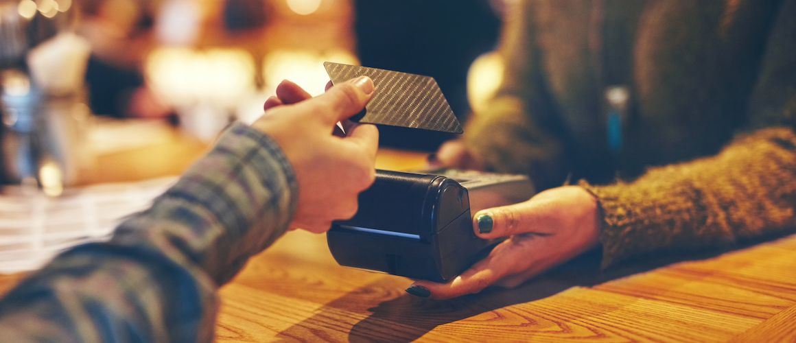 An illustration showing a hand holding a credit card for payment.