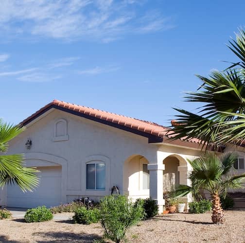 White stucco ranch home with Spanish style roof tiles and xeriscaping.