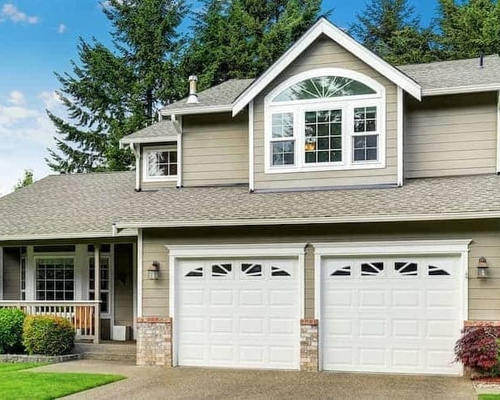 A white and grey two storey house with a broad driveway.