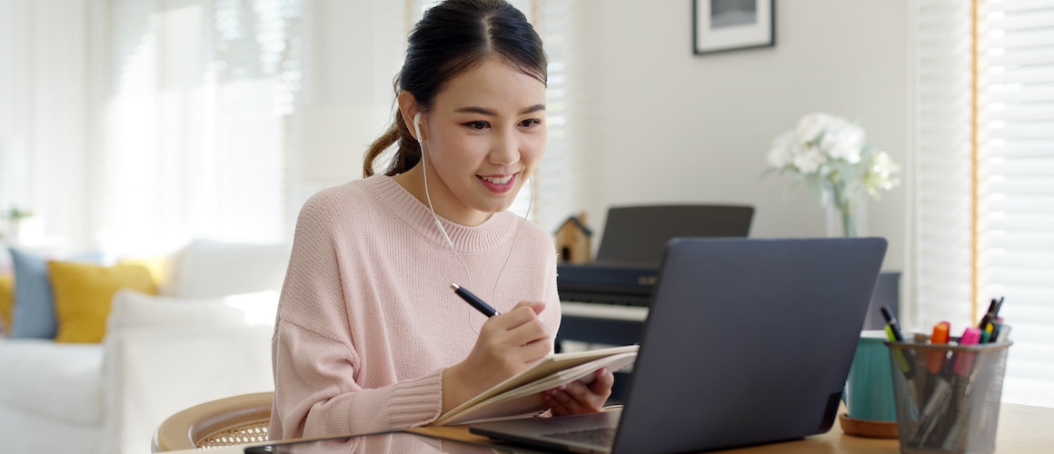 Asian woman on computer with headphones